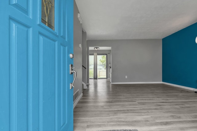foyer entrance featuring visible vents, baseboards, and wood finished floors