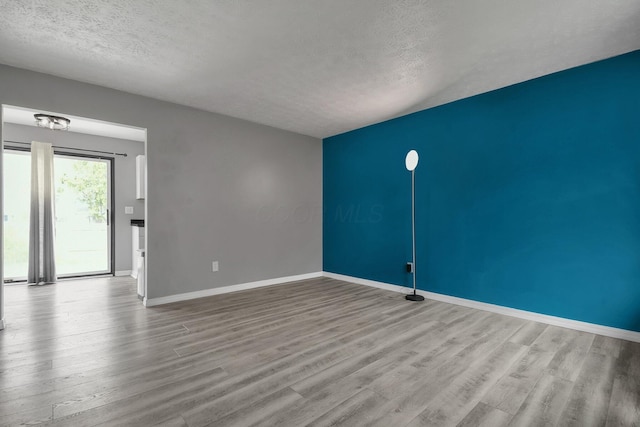 empty room with baseboards, wood finished floors, and a textured ceiling