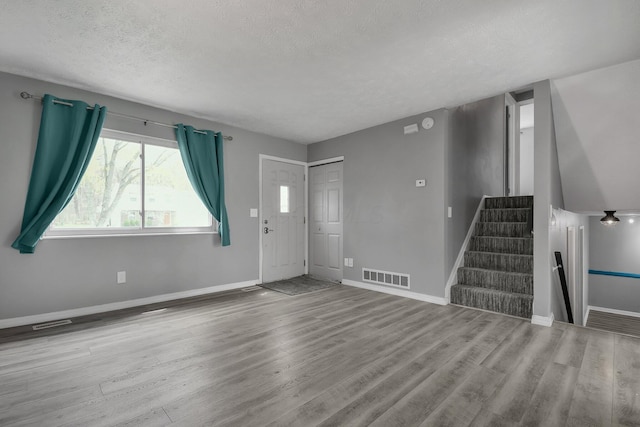 interior space with visible vents, baseboards, a textured ceiling, stairway, and wood finished floors