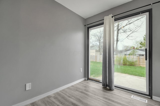 doorway to outside featuring wood finished floors, baseboards, visible vents, and a wealth of natural light