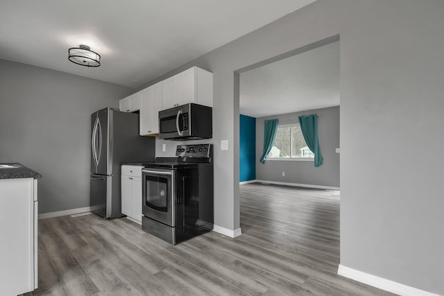 kitchen with light wood-style flooring, white cabinets, baseboards, and stainless steel appliances