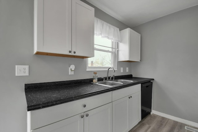 kitchen featuring dark wood-style floors, black dishwasher, dark countertops, white cabinets, and visible vents