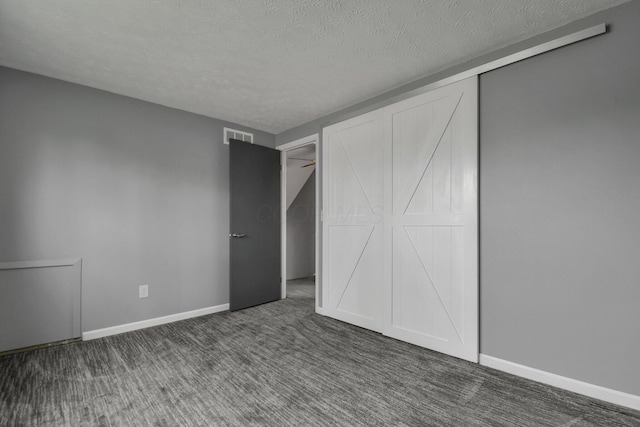 unfurnished bedroom featuring a textured ceiling, a closet, visible vents, carpet flooring, and baseboards