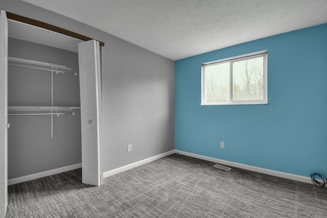 unfurnished bedroom featuring visible vents, baseboards, a closet, carpet, and a textured ceiling