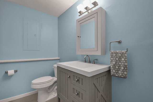 half bath with electric panel, vanity, baseboards, and toilet