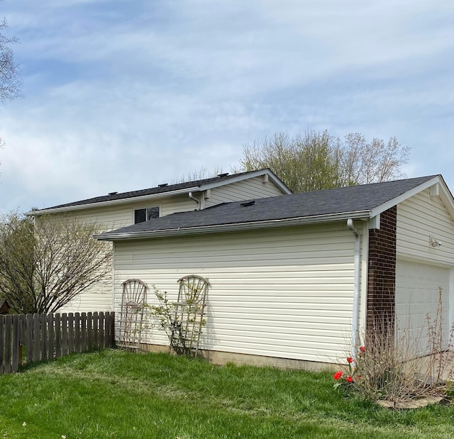 view of home's exterior featuring a garage, fence, and a lawn