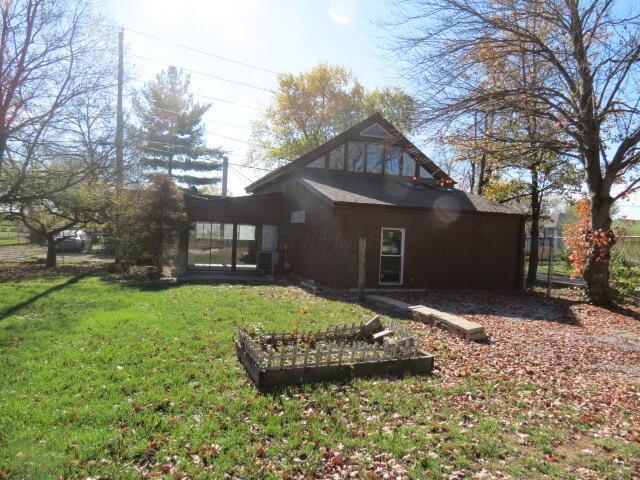 11 Plumb St, Lockbourne, OH 43137 - back of property featuring a sunroom, fence, and a lawn