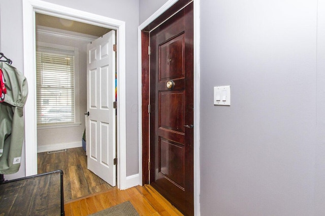 corridor featuring wood finished floors, baseboards, and visible vents