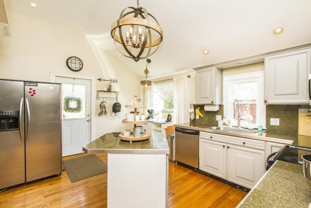 kitchen featuring stainless steel appliances, light wood-style floors, a notable chandelier, and a sink