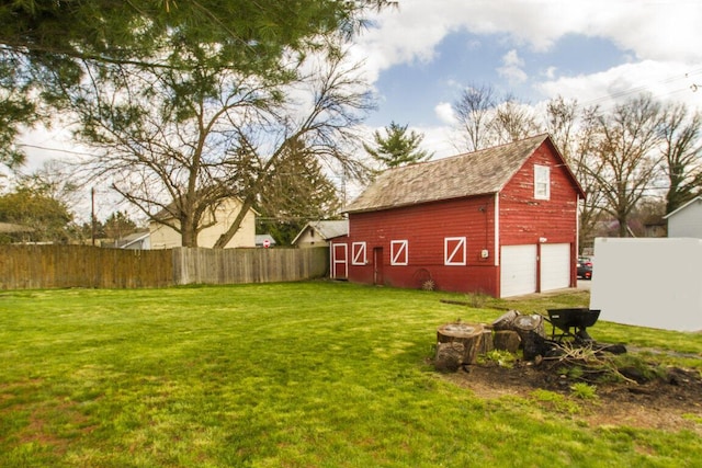 view of yard featuring a barn, a garage, fence, and an outdoor structure