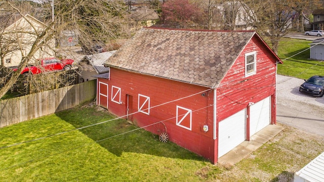 view of barn with fence and a lawn