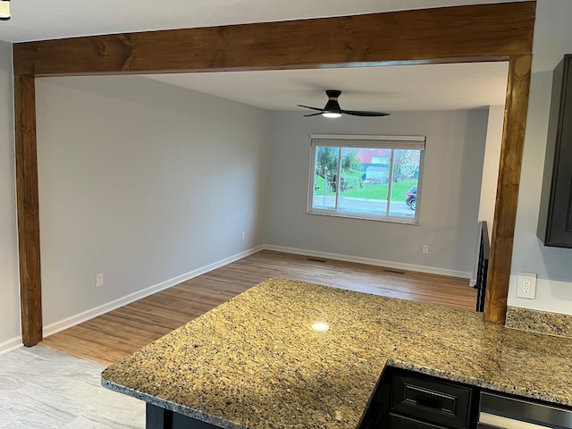 interior space featuring light wood-style flooring, beamed ceiling, baseboards, and a ceiling fan