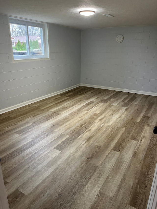 empty room featuring concrete block wall and wood finished floors