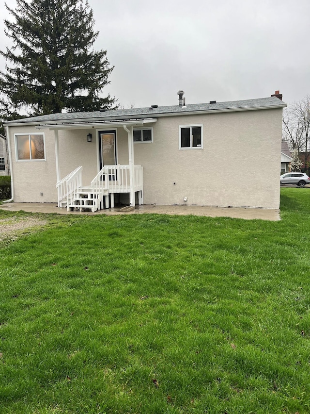 rear view of house featuring stucco siding and a lawn