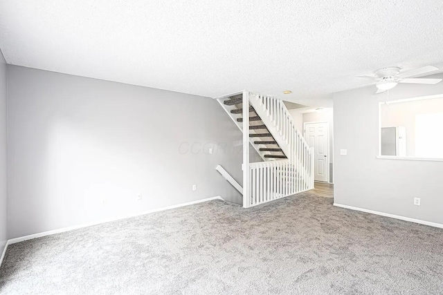unfurnished living room featuring carpet floors, baseboards, a ceiling fan, and a textured ceiling