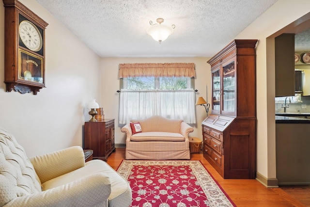 sitting room featuring light wood-type flooring and a textured ceiling