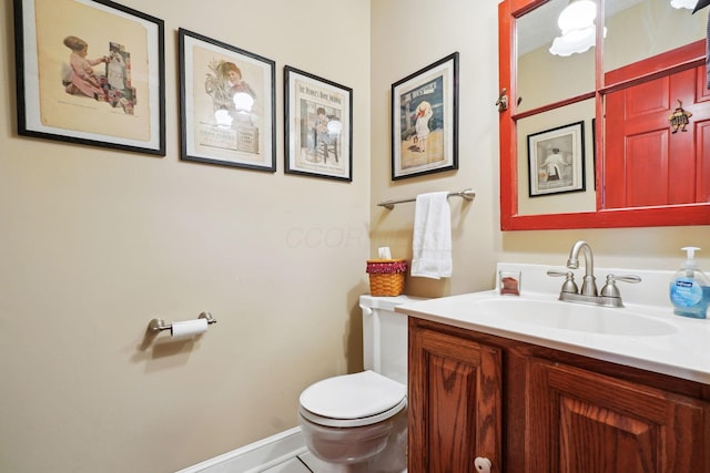 bathroom with toilet, vanity, and baseboards