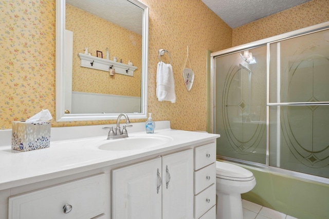 bathroom featuring a textured ceiling, vanity, enclosed tub / shower combo, and wallpapered walls