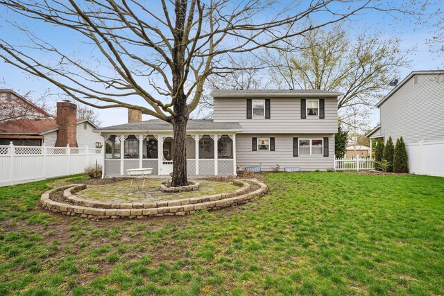 rear view of house with a yard, a fenced backyard, a sunroom, and a chimney