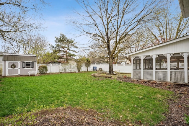 view of yard featuring an outbuilding, a fenced backyard, a sunroom, and a shed
