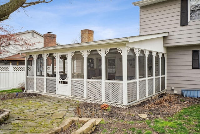 exterior space with a patio area, fence, a sunroom, and a chimney
