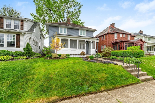 american foursquare style home with a chimney, a front yard, and a sunroom