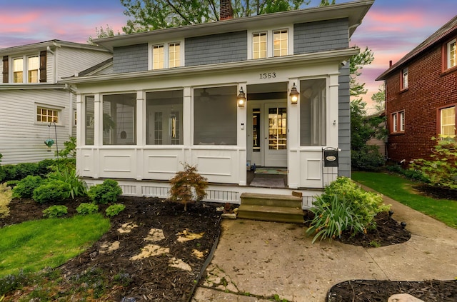 view of front of home with a chimney and a sunroom