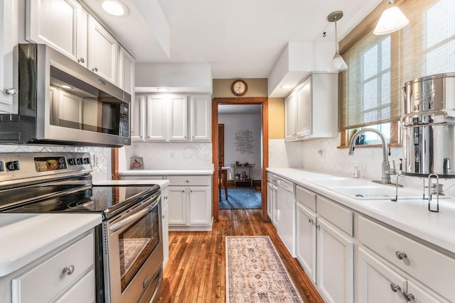 kitchen featuring dark wood finished floors, stainless steel appliances, light countertops, white cabinets, and a sink