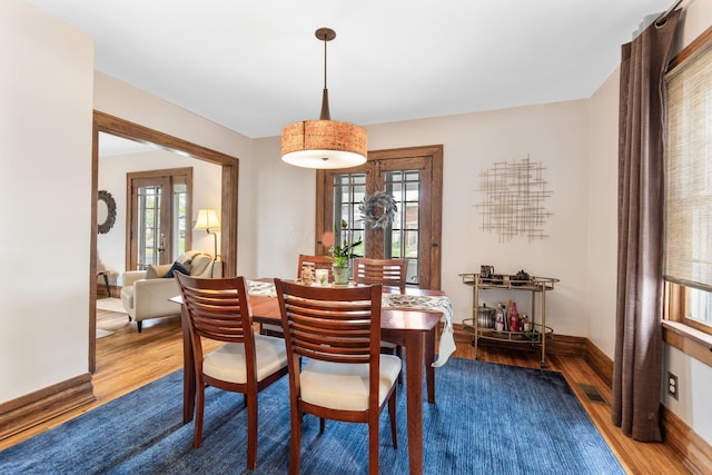 dining space with visible vents, wood finished floors, and baseboards