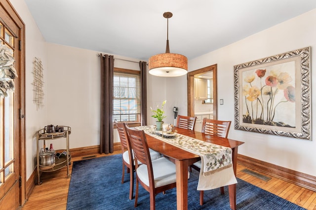 dining room with baseboards, visible vents, and light wood finished floors