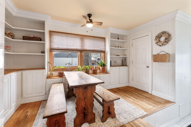 dining area with light wood-style floors, a ceiling fan, ornamental molding, and built in shelves