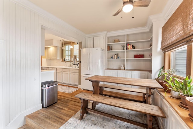 dining room with ceiling fan, crown molding, and light wood-style flooring