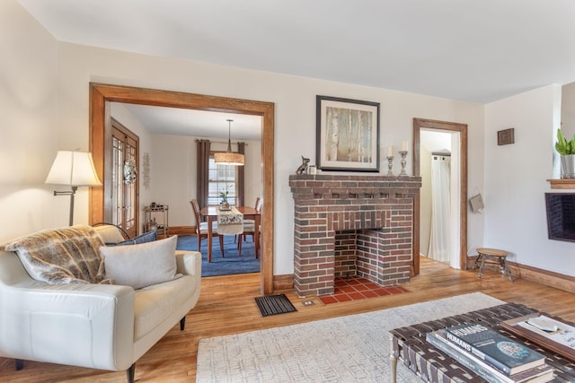 living area featuring a fireplace, wood finished floors, and baseboards