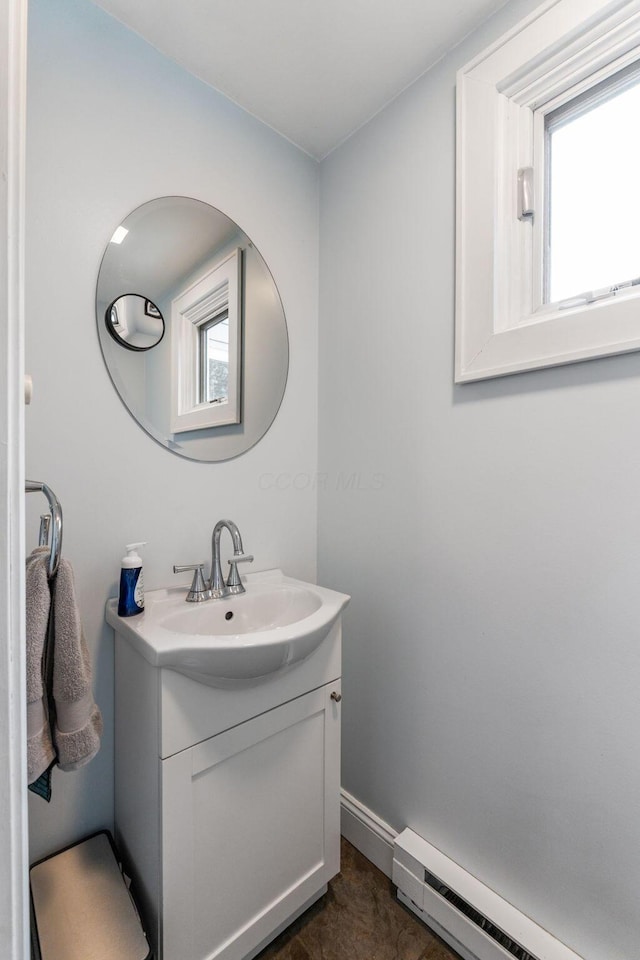 bathroom featuring baseboards, baseboard heating, vanity, and a healthy amount of sunlight