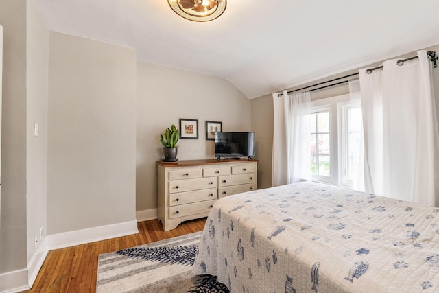 bedroom featuring baseboards, vaulted ceiling, and light wood-type flooring