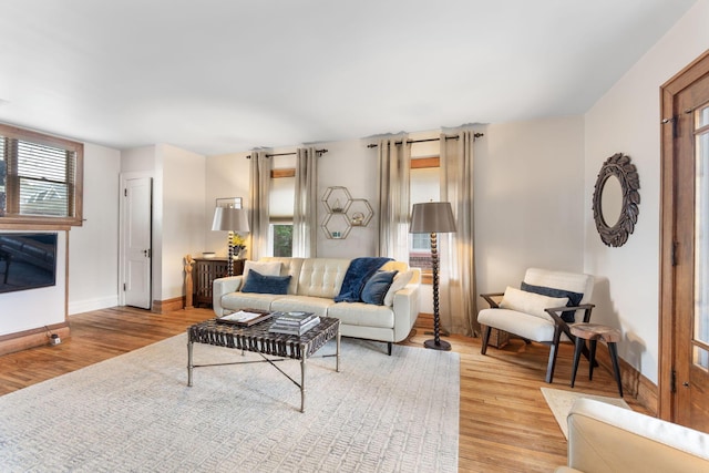 living area featuring a healthy amount of sunlight, light wood-type flooring, and baseboards