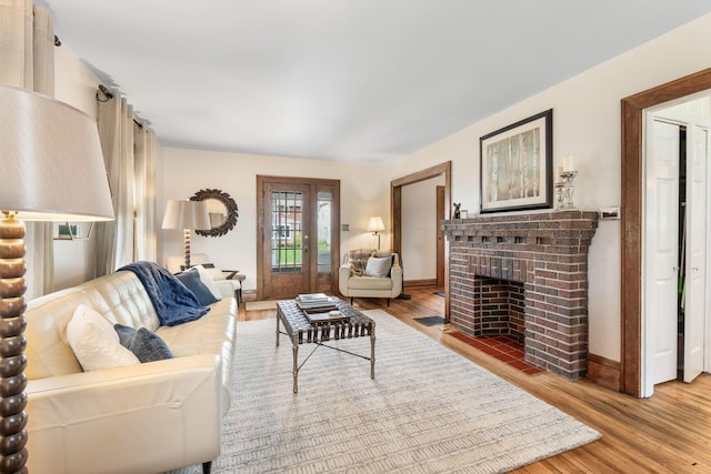 living area with a fireplace, wood finished floors, and baseboards