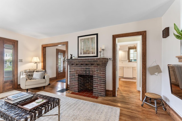 living area featuring a fireplace, baseboards, wood finished floors, and a healthy amount of sunlight