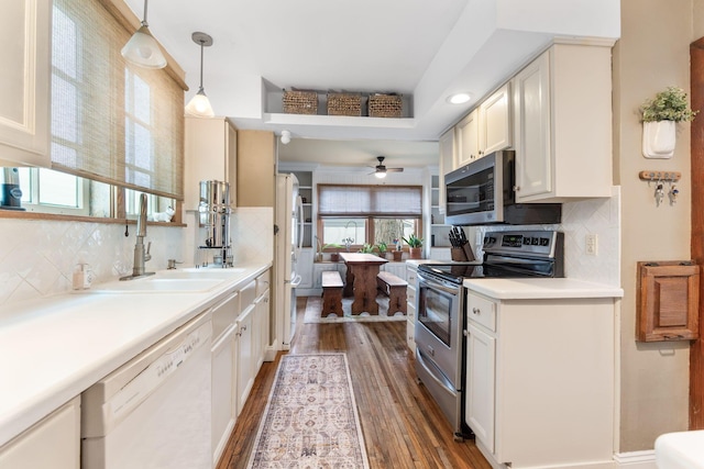 kitchen featuring ceiling fan, appliances with stainless steel finishes, decorative backsplash, and dark wood finished floors