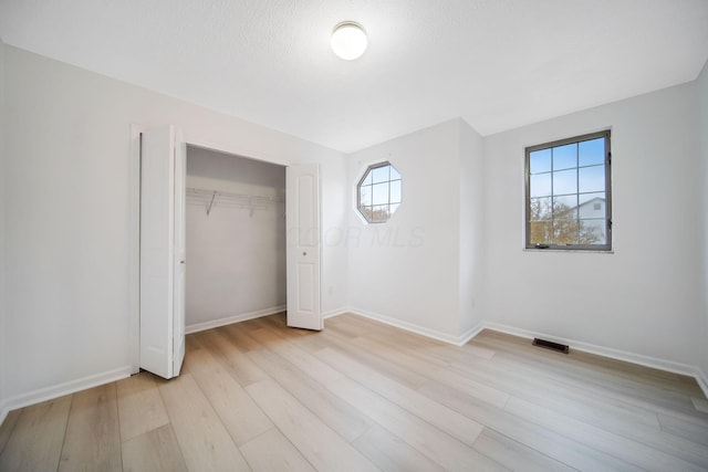 unfurnished bedroom with visible vents, a closet, baseboards, and light wood-style floors