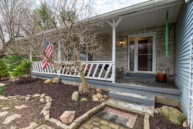 view of exterior entry featuring covered porch and stone siding