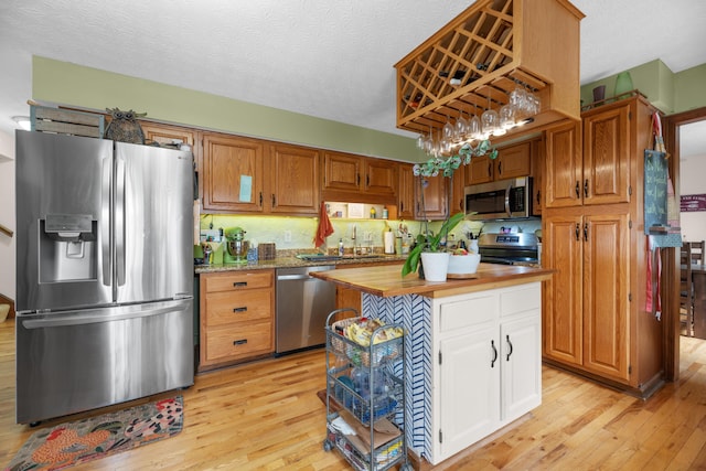 kitchen featuring a sink, light wood-type flooring, a center island, white cabinets, and appliances with stainless steel finishes