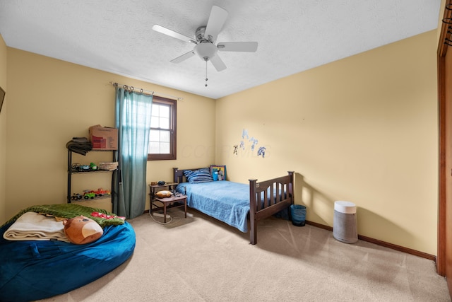 carpeted bedroom with a textured ceiling, ceiling fan, and baseboards
