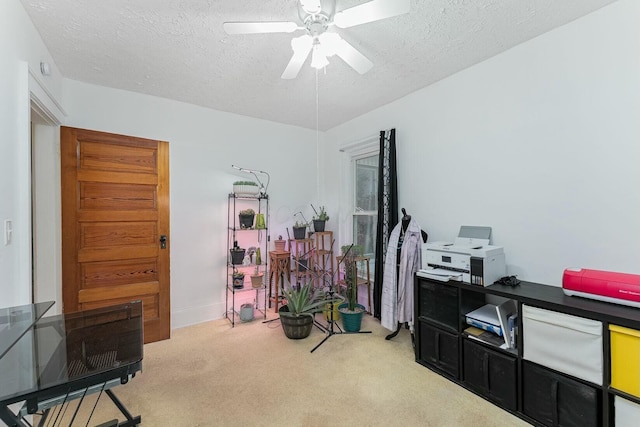 home office featuring ceiling fan, light carpet, and a textured ceiling