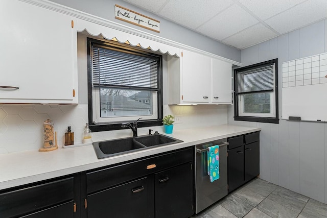 kitchen featuring dark cabinets, white cabinetry, dishwasher, light countertops, and a sink