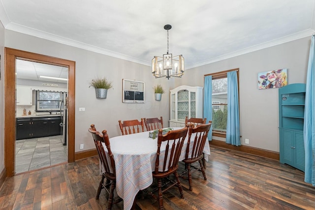 dining room with crown molding, wood-type flooring, baseboards, and a notable chandelier