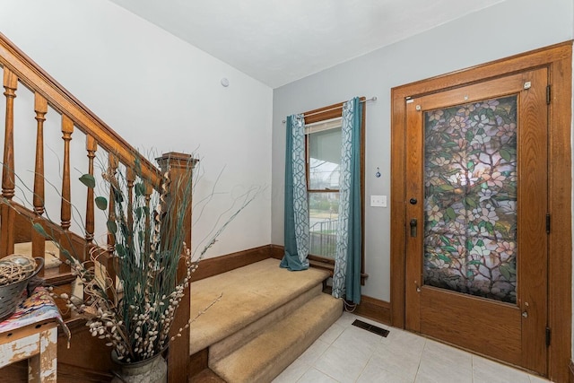 foyer featuring visible vents, baseboards, light tile patterned flooring, and stairs