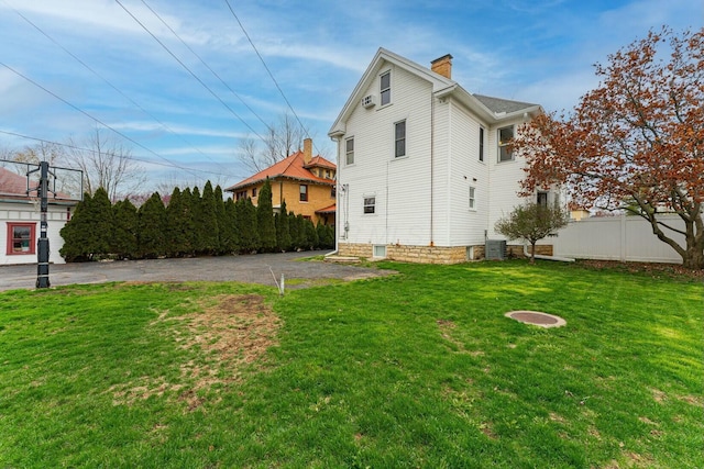 view of side of property with a yard, fence, and a chimney