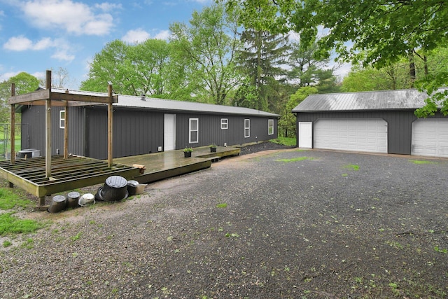 view of front of house with a detached garage, a wooden deck, and an outbuilding