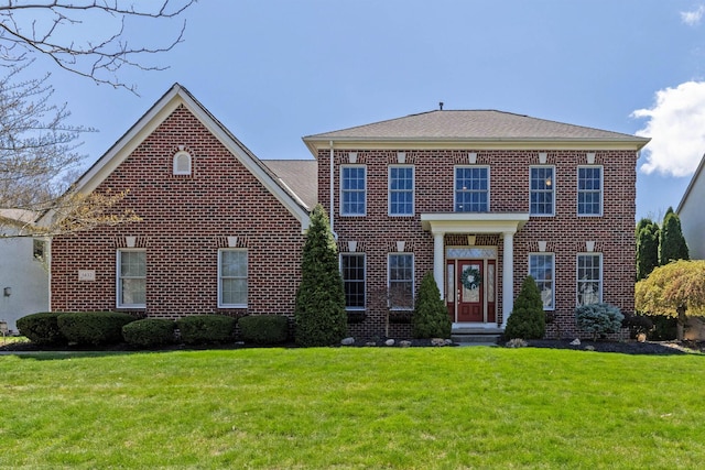 georgian-style home featuring brick siding and a front lawn